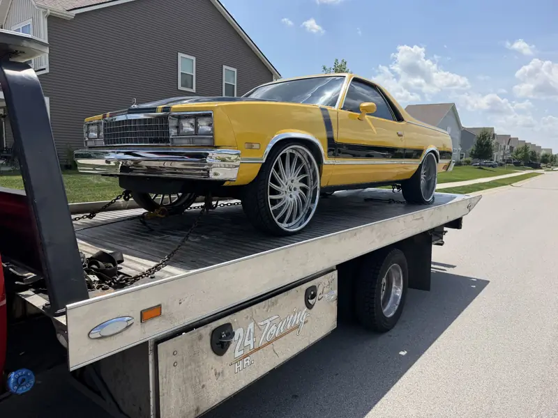 Yellow custom car on big rims strapped on the Elite Detroit Towing flatbed